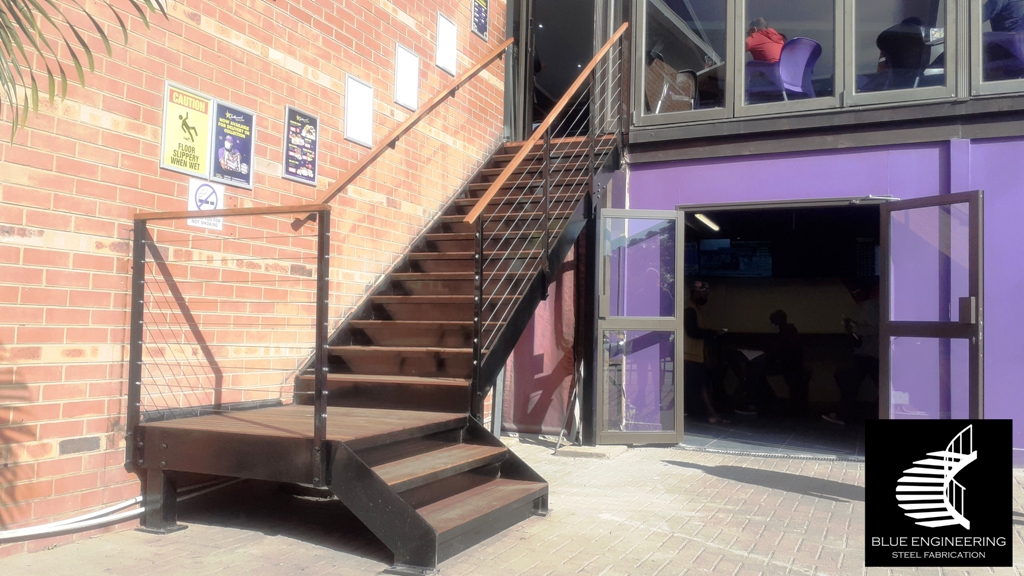 Steel staircase with flat plate stringers and steel treads clad with balau, installed with cable baustrades. Johannesburg, Pretoria, Durban, Gauteng, KwaZulu Natal